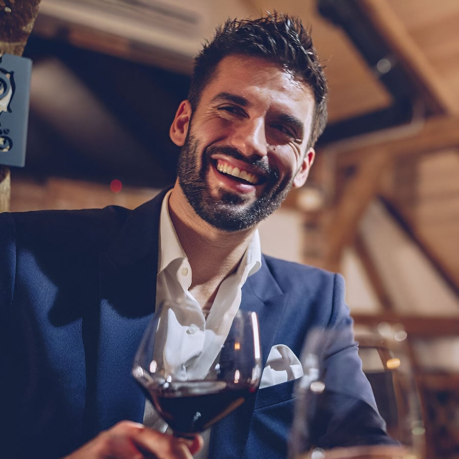 hombre sonriendo con una copa de vino